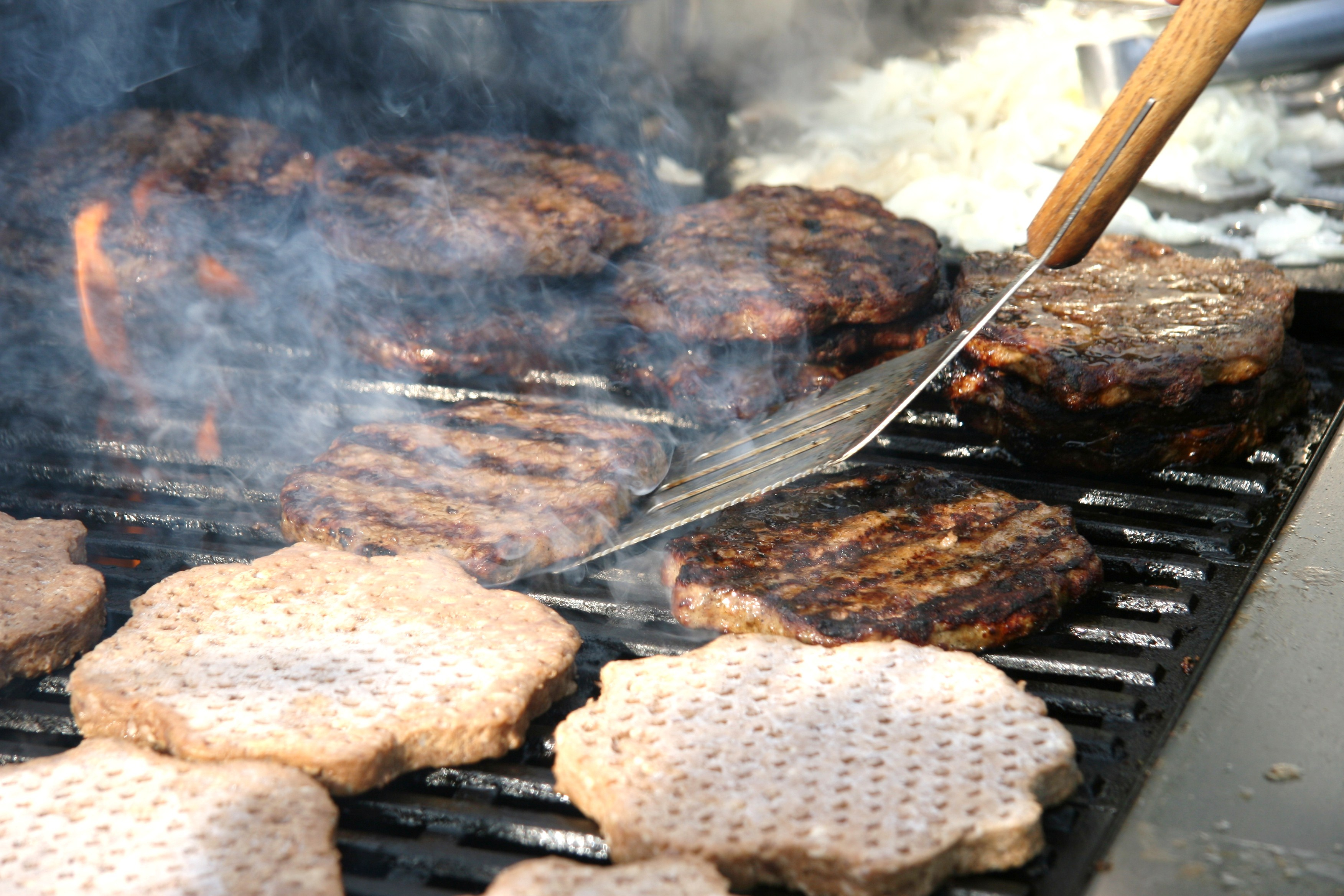 multiple hamburgers on a grill over a fire