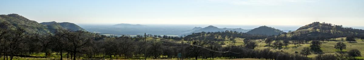 Overlooking a grassy field, a two lane road, and foothills.